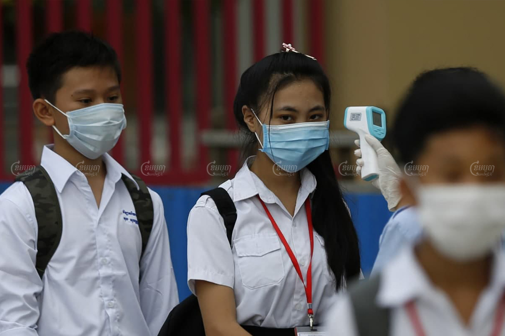 A student from Bak Touk high school in Phnom Penh has her temperature checked before entering the classroom in September. Panha Chhorpoan