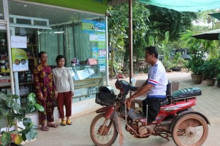 People affected by severe flooding in September and October receive humanitarian aid from two non-governmental groups at a cash transfer service in Siem Reap province. DCA