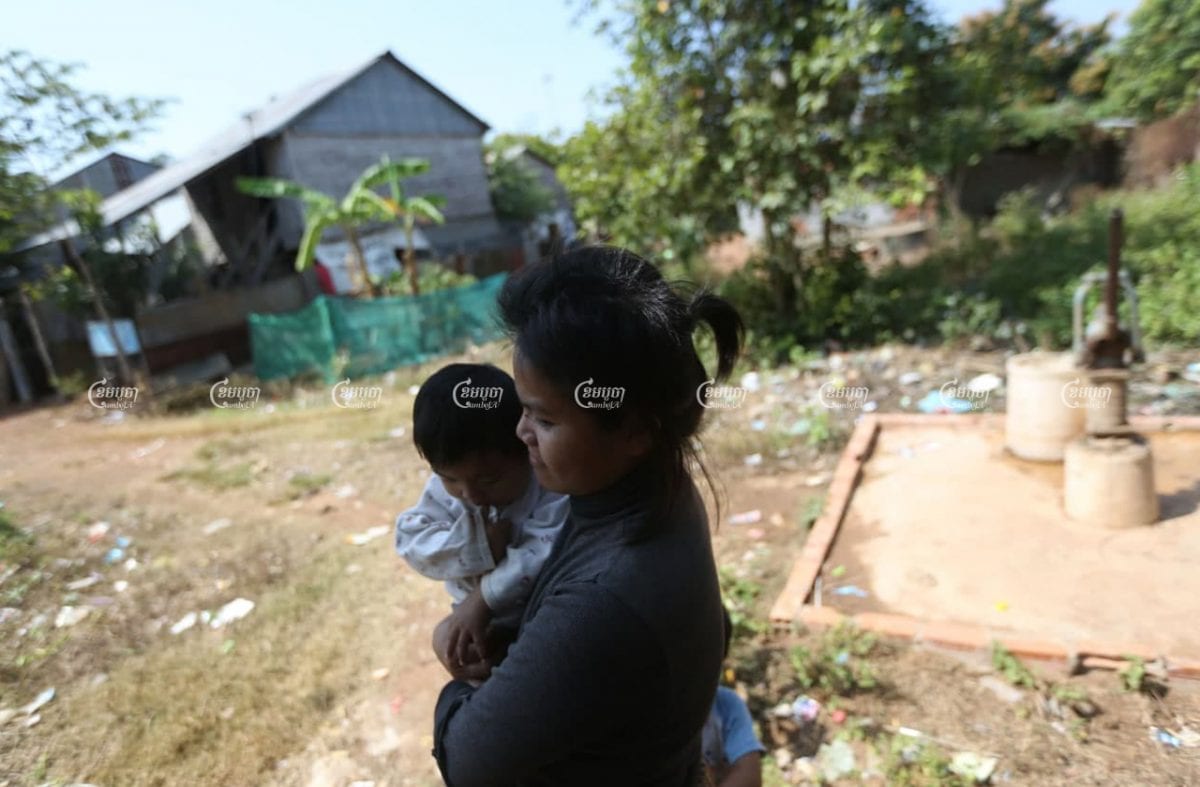 Chey Sopheak, a former resident of Borei Keila, carries her child near her Sras Por village home in February 2021. Her hair is short because she sold it to pay for medical treatment. CamboJA/ Pring Samrang