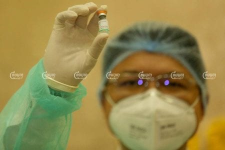 A medial staffer inspects a dose of the Covid-19 vaccine during the 1st day of injections at Phnom Penh’s Calmette Hospital last month. CamboJA/ Pring Samrang