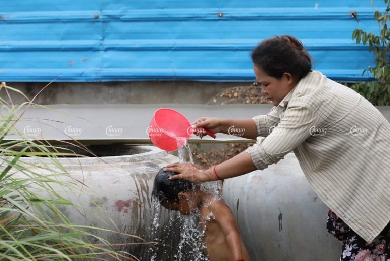 A woman showers a child in water purchased from a private company in outer Phnom Penh, March 21. CamboJA/Pring Samrang