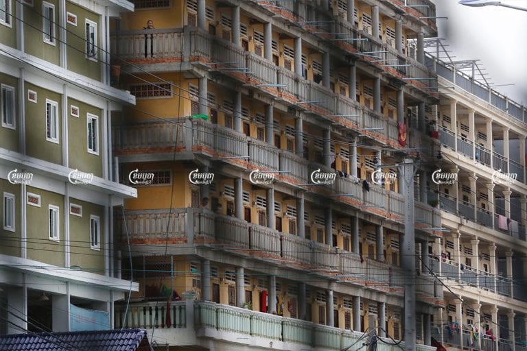 After a small Monday morning protest in their neighborhood demanding rent exemptions, suspended garment workers stand on the balconies of their rental apartments within a red zone at the Stung Meanchey III commune in Phnom Penh, May 10, 2021. CamboJA/ Panha Chhorpoan