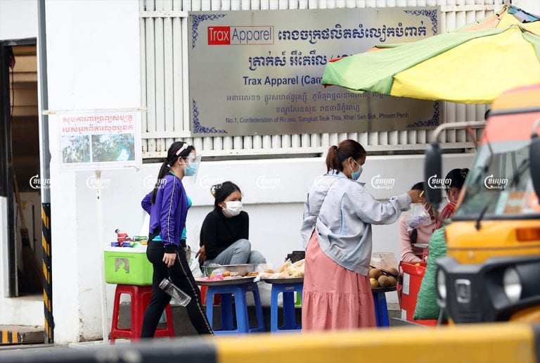 Garment workers at their lunch break outside a factory where workers recently tested positive for COVID-19, in Phnom Penh, May 24, 2021. CamboJA/ Pring Samrang