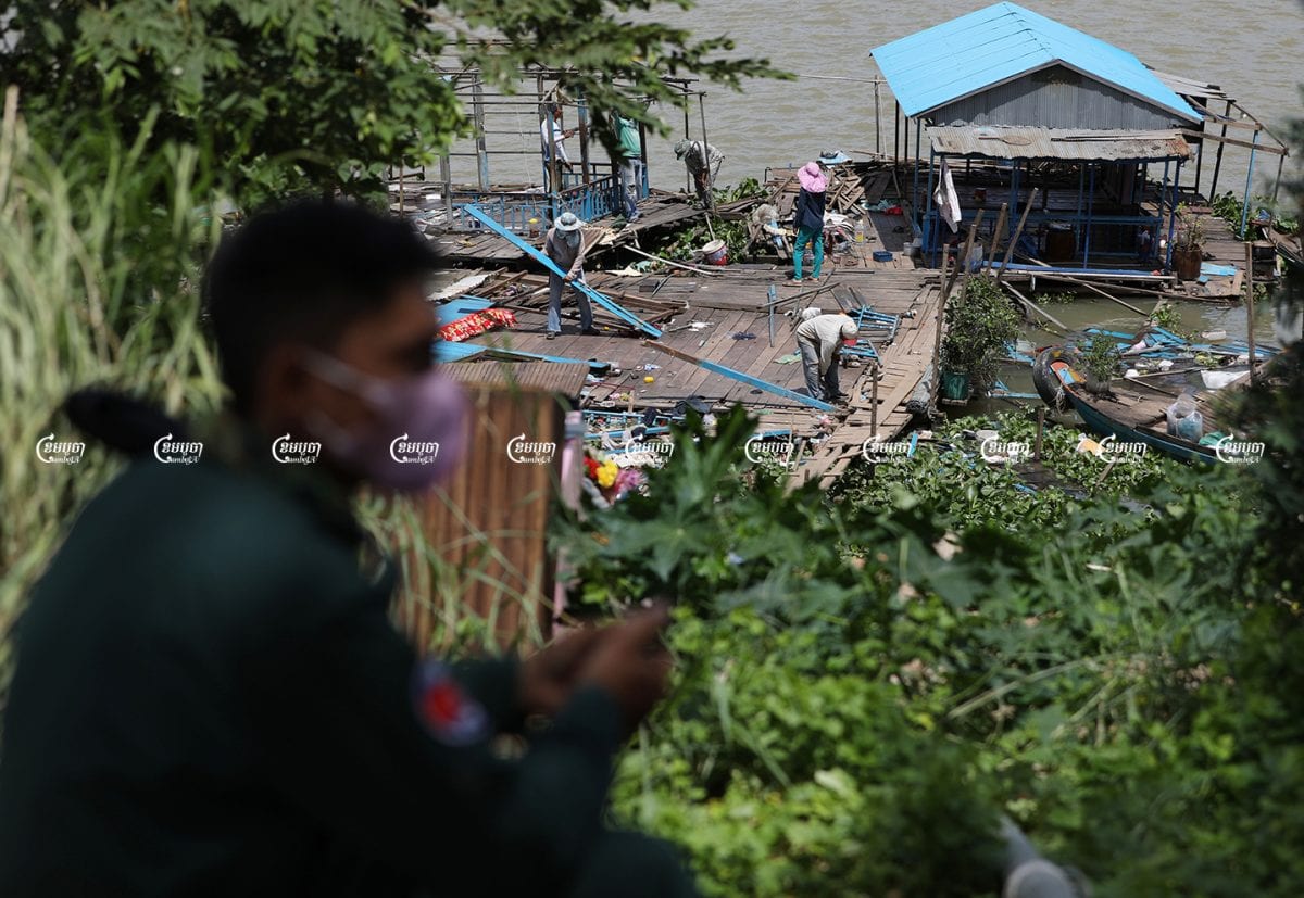 A police officer monitors ethnic Vietnamese people while they move their floating house in Chroy Changvar district, June 14, 2021. CamboJA/ Pring Samrang