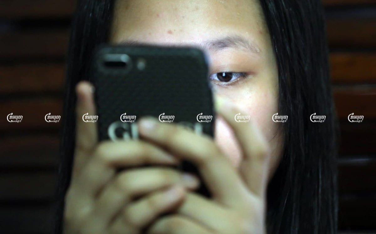 A girl looks at her smartphone while at her home in Phnom Penh, July 14, 2021.CamboJA/ Pring Samrang