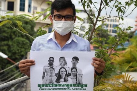 An NGO staff member holds up a photo of imprisoned Mother Nature environmental activists as part of a social media campaign calling for the six youths' release.