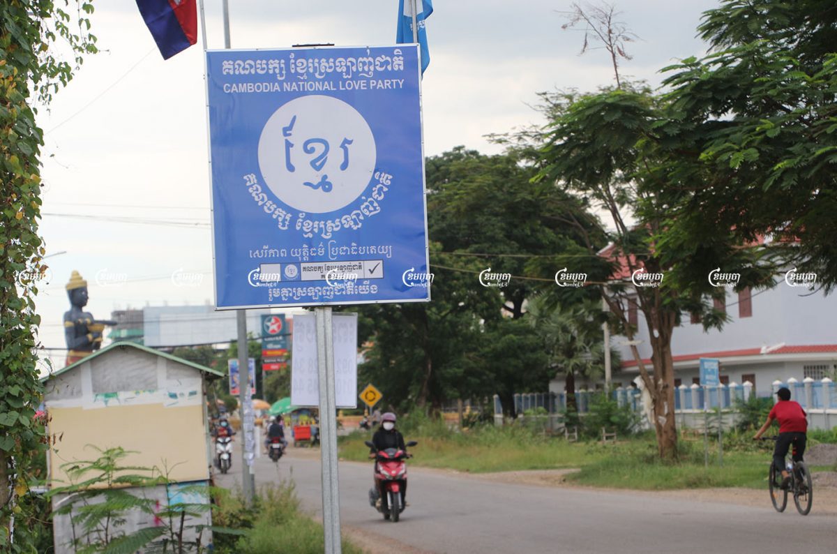 Drivers pass a sign for the newly formed Cambodia National Love Party in Battambang city. Photo taken on August 17, 2021. CamboJA/ Panha Chhorpoan