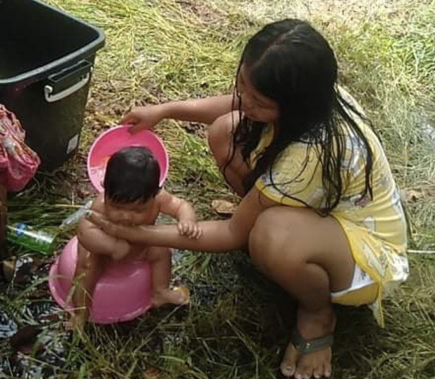 Ren Sreyna bathes her baby at the makeshift border camp where returning migrant workers are staying until the border checkpoint reopens. Supplied