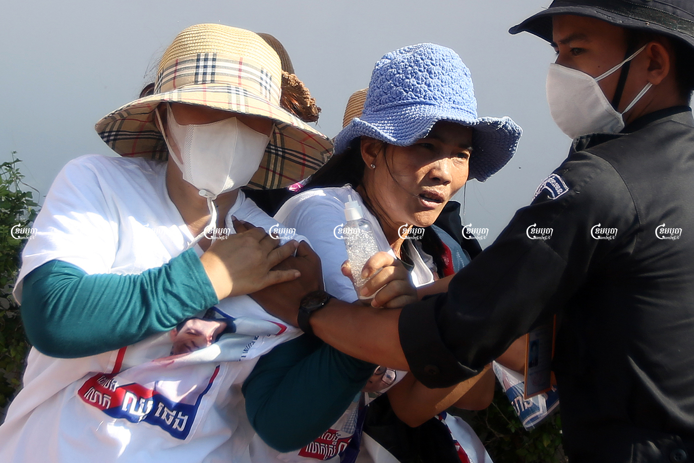 Security personnel seize banners from relatives of imprisoned CNRP members at a small demonstration. Protestors had submitted a petition to a UN office in Phnom Penh seeking help in freeing their family members, Picture taken on June 4, 2021. CamboJA/ Pring Samrang