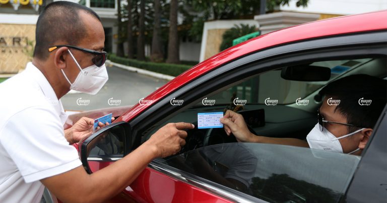 A Phnom Penh hotel security guard checks a costumer's COVID-19 vaccination card before allowing them to enter, October 11, 2021. CamboJA/ Pring Samrang