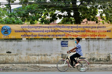 A man rides a bicycle past a banner asking people to confirm their personal information and register to vote ahead of the 2022 commune election, October 4, 2021. CamboJA/ Panha Chhorpoan