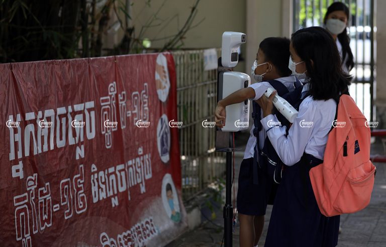 A girl lifts her brother for a temperature check before entering class in Phnom Penh. November 1, 2021. CamboJA/ Pring Samrang