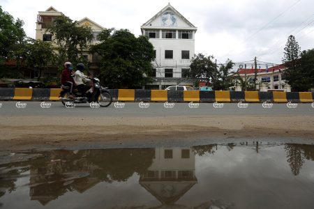 A man drives a motorcycle with a woman past the former Cambodia National Rescue Party headquarters in Phnom Penh. Picture taken May 24, 2021. CamboJA/ Pring Samrang