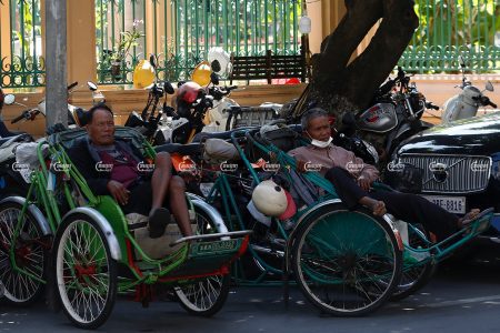Cyclo drivers Choy Pich 78 and Sin Met 65 waiting for customers along a street in Phnom Penh, December 6, 2021. CamboJA/ Panha Chhorpoan