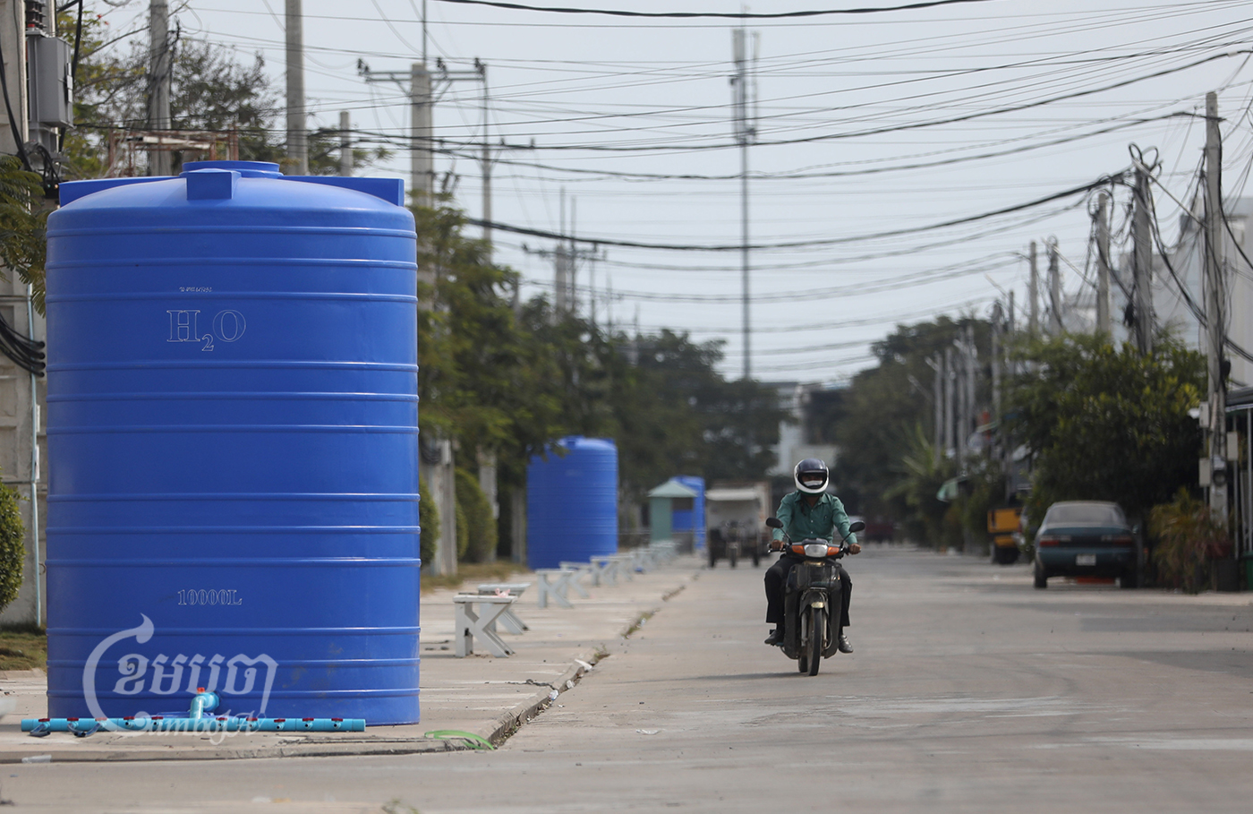 A man drives his motorbike past a water basin in Borey Piphup Thmey Chhouk Va II on the outskirts of the city on Feb 1, 2022. CamboJa/ Pring Samrang