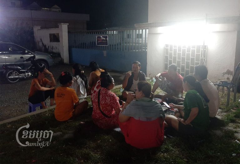 Workers laid off from Canteran Apparel (Cambodia) Co. Ltd sit guard outside the factory, which closed without paying them compensation. Photo taken on May 9, 2022. CamboJA/ Va Sopheanut