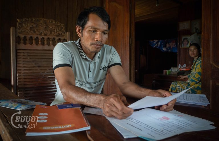 Pu Lu village community representative Maly Kim holds one of the agreements he signed after five years of negotiations, but he worries the company will not deliver on its promises. (Jack Brook/CamboJA)