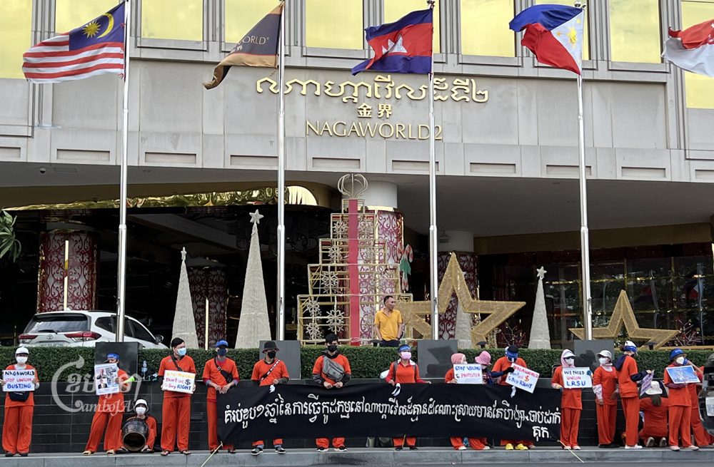NagaWorld employees, clad in orange jumpsuits to symbolize the arrest of union leader Chhim Sithar, protest in front of the casino to mark the one year anniversary of their ongoing strike on December 18, 2022. (CamboJA/ Sovann Sreypich).