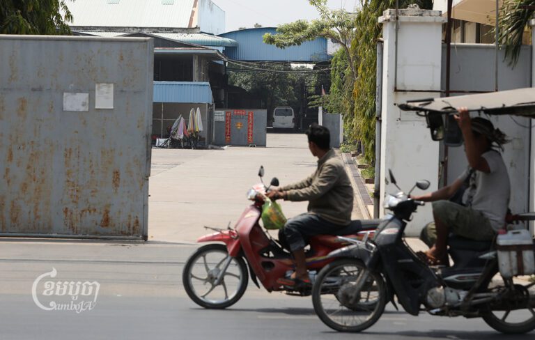 Men drive past the Great Union Factory on the outskirts of Phnom Penh, which has had to suspend a number of its workers due to decreased orders, March 07, 2023. CamboJA/ Pring Samrang