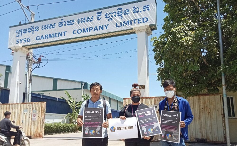 Three union members hold banners in front of SYSG Garment Company Limited to ask the factory's owner to reinstate vice president Yoeun Yim on June 21, 2023. (Supplied)