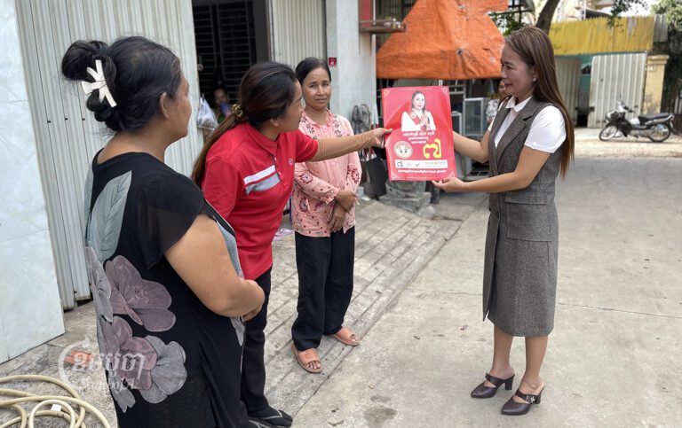 Soeung Sothy, president of Women for Women Party, meets people in Phnom Penh’s Meanchey district which shows a leaflet of her party policy, June 23, 2023. CamboJA/Pring Samrang
