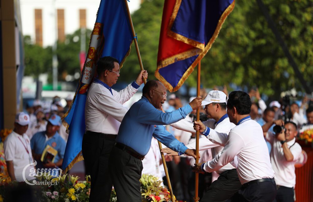 Hun Sen hands over the ruling CPP's flag to Hun Manet to lead an election campaign on July 1, 2023. (CamboJA/Pring Samrang)