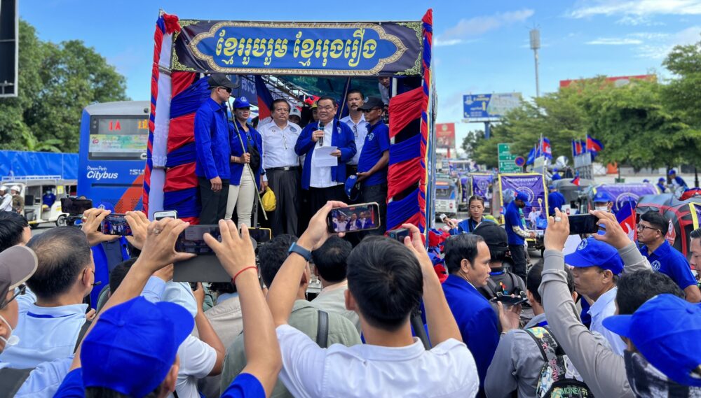 Nhek Bun Chhay, president of the Khmer National United Party (KNUP), accompanied by his vice president Yem Ponhearith, stands on the truck to speak to his supporters outside Freedom Park in Russei Keo district, Phnom Penh on first day of national election campaign on July 1, 2023. (CamboJA/ Sovann Sreypich)