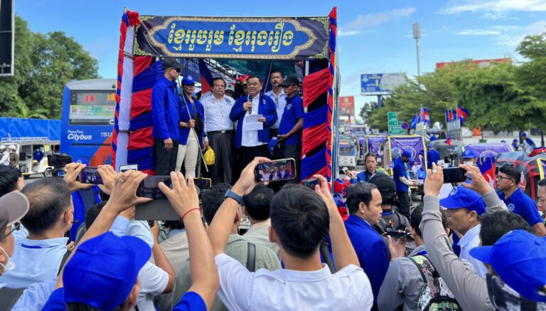 Nhek Bun Chhay, president of the Khmer National United Party (KNUP), accompanied by his vice president Yem Ponhearith, stands on the truck to speak to his supporters outside Freedom Park in Russei Keo district, Phnom Penh on first day of national election campaign on July 1, 2023. (CamboJA/ Sovann Sreypich)