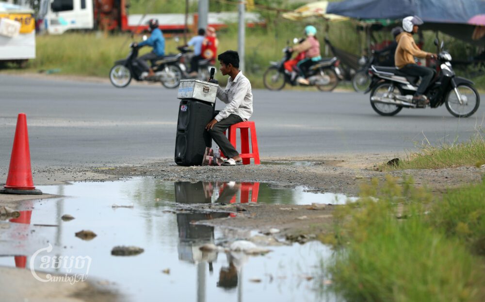 A disabled man sings for tips along a street on the outskirts of Phnom Penh on August 4, 2023. (CamboJA/Pring Samrang)