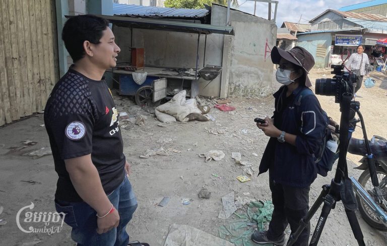 A female journalist interviews a source at a field in Poipet city on December 30, 2022. (CamboJA/ Pring Samrang)