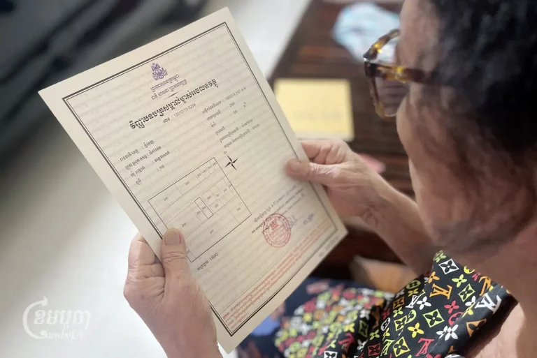 A woman looks at her land title certificate. CamboJA/Pring Samrang