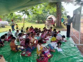 A community volunteer of World Vision Cambodia teaches children at a camp shelter at Preah Vihear province. (Photo: World Vision Cambodia)