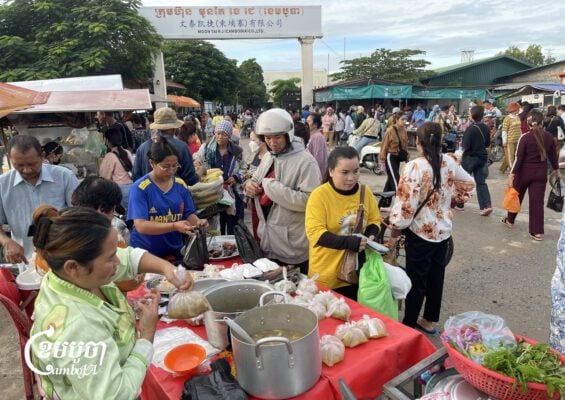 Garment workers buy food at a stall in front of a factory in Kandal province after arriving early in the morning before their shift. Sept. 3, 2025. (CamboJA/ Pring Samrang)