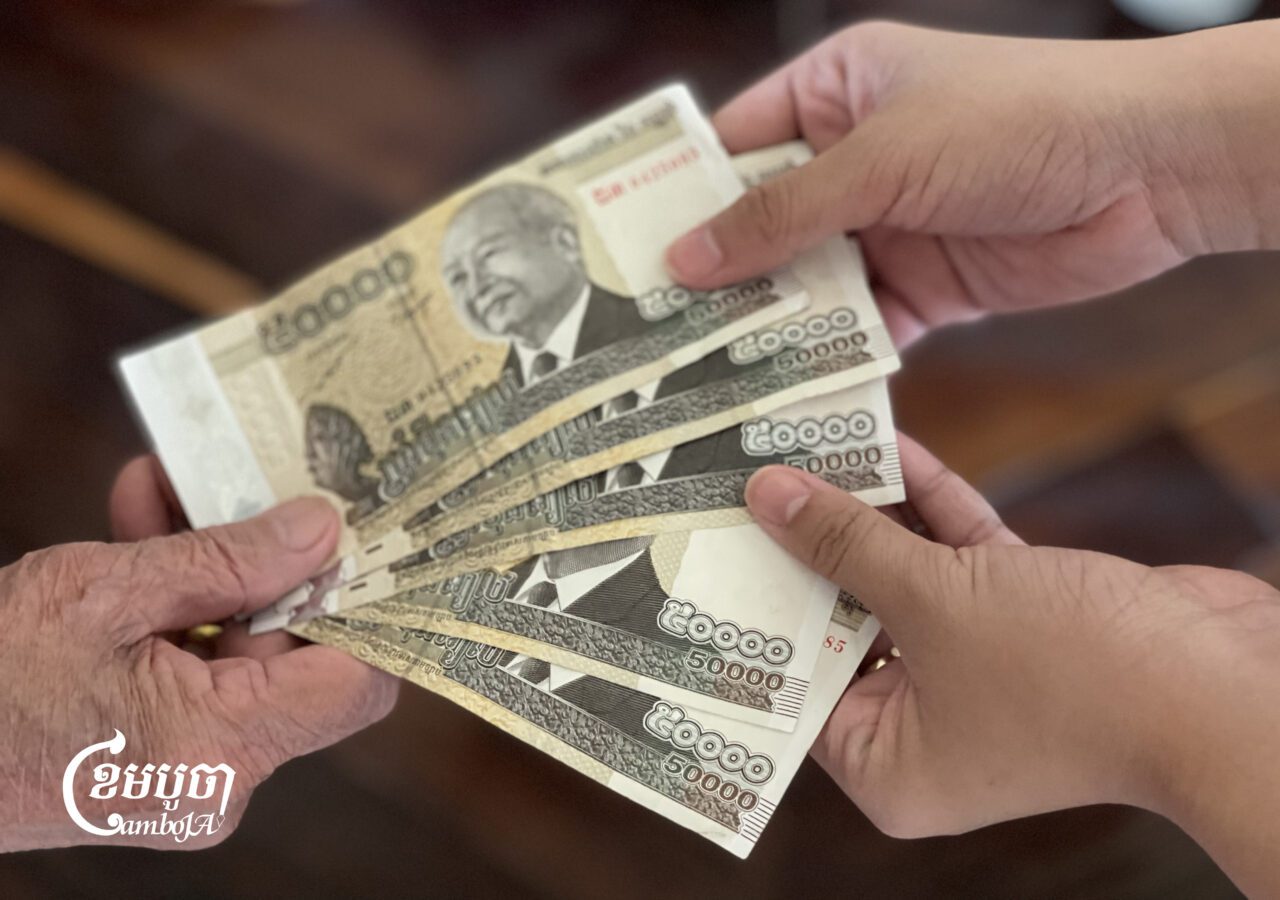 An elderly woman pays for her things at a market in Phnom Penh, September 9, 2025. (CamboJA/Pring Samrang)