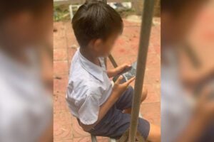 A boy uses his mother’s smartphone in Kampong Cham province. Sept. 3, 2025. (Photo: Chanleap Pin)