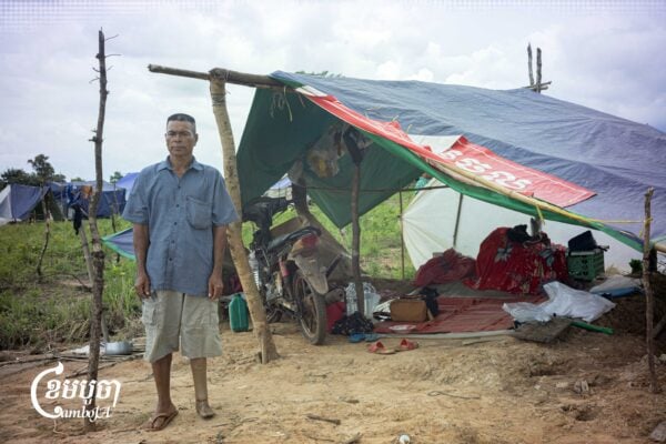 Nol Ny, 59, a former soldier who lost his left leg after stepping on a landmine, stands in front of his tent at a displacement camp in Preah Vihear province, September 6, 2025. (CamboJA/ Mech Choulay)