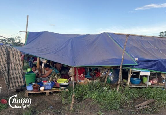 A mother and her daughter prepare dinner, while family members chat in a tent at the 5,000 Bodhi Tree Pagoda displacement camp in Kulen district, Preah Vihear province, on September 14, 2025. (CamboJA/Pa Tongchen)
